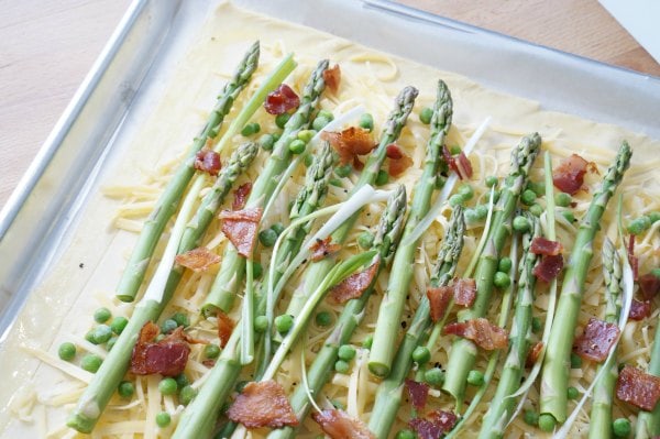 This spring tart combines seasonal asparagus, green onions, peas, gouda and bacon - because everything tastes better with bacon. Tarts are a fabulous addition to the kids' lunch box or alongside a green salad for lunch or dinner.​ | YMCFood | YummyMummyClub.ca