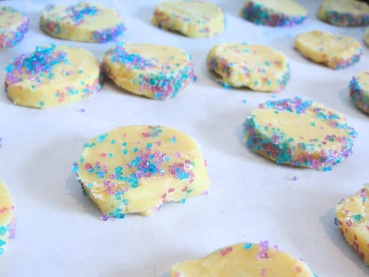 freezer cookies sliced and covered with colorful sugar on parchment paper lined baking sheet
