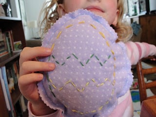 kid proudly holding up kid-made easter egg pillow