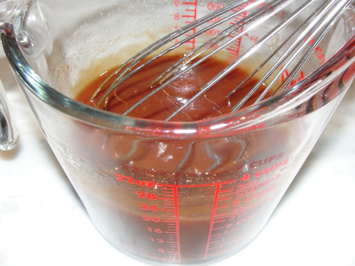ingredients for bbq sauce in measuring cup with whisk
