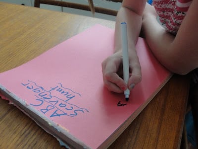 child writing abc scavenger hunt game on paper