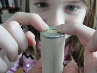 child gluing washer on top of wood dowel for weather vane project