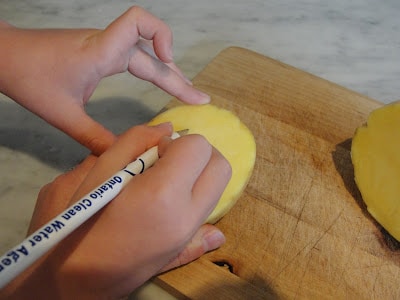 child drawing circle on potato
