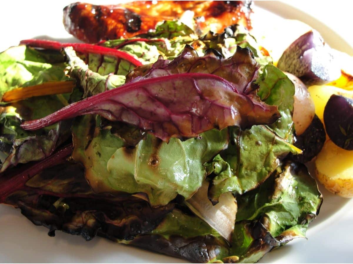 simple bbq swiss chard on plate with potatoes and chicken wings