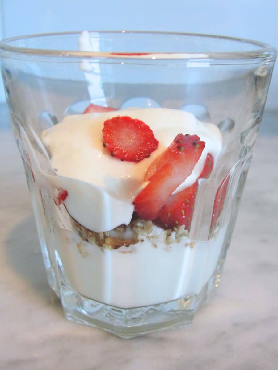 glass filled with homemade vanilla yogurt with strawberries and granola
