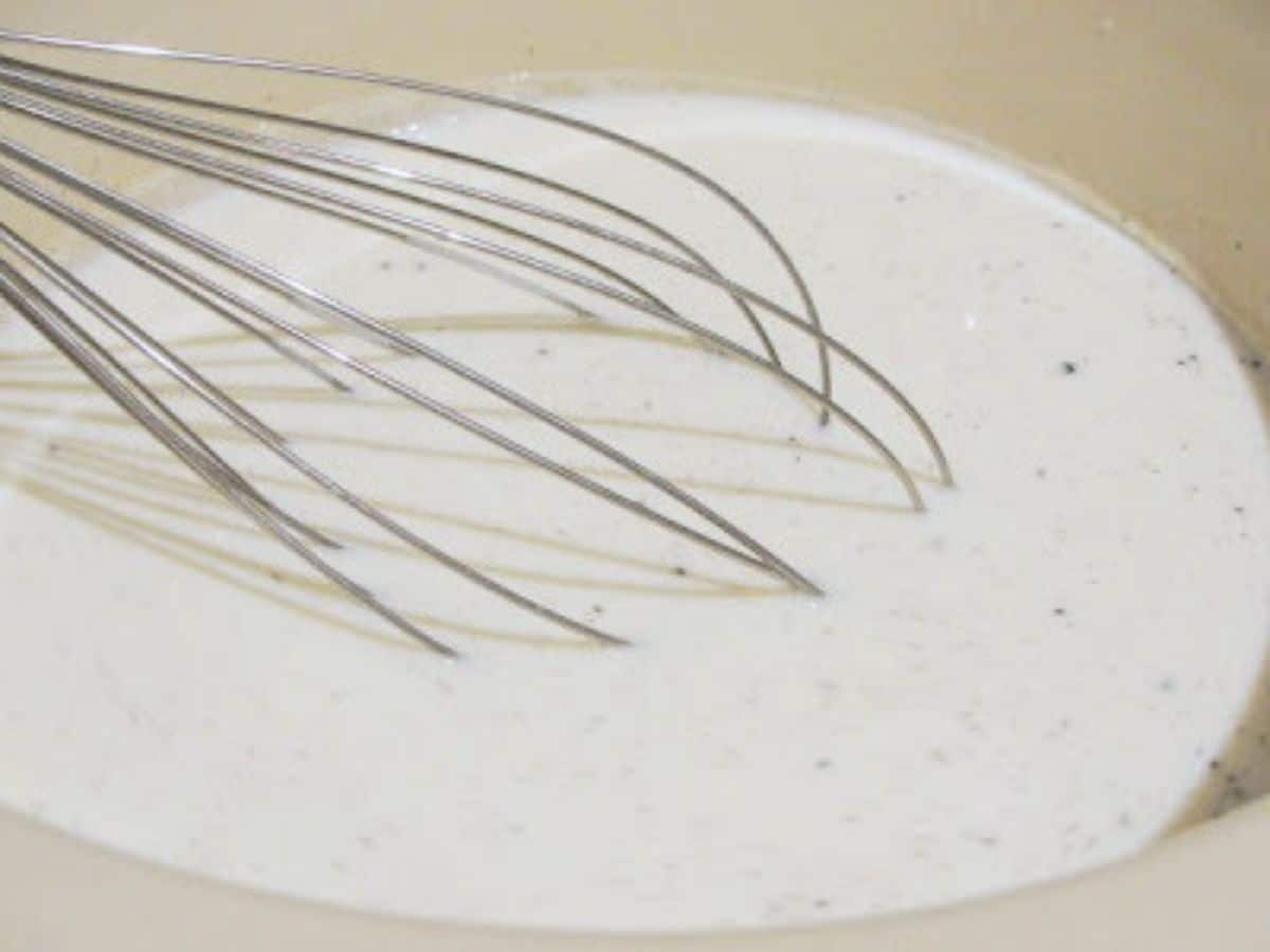 milk, live yogurt and vanilla bean seeds with whisk in crockpot