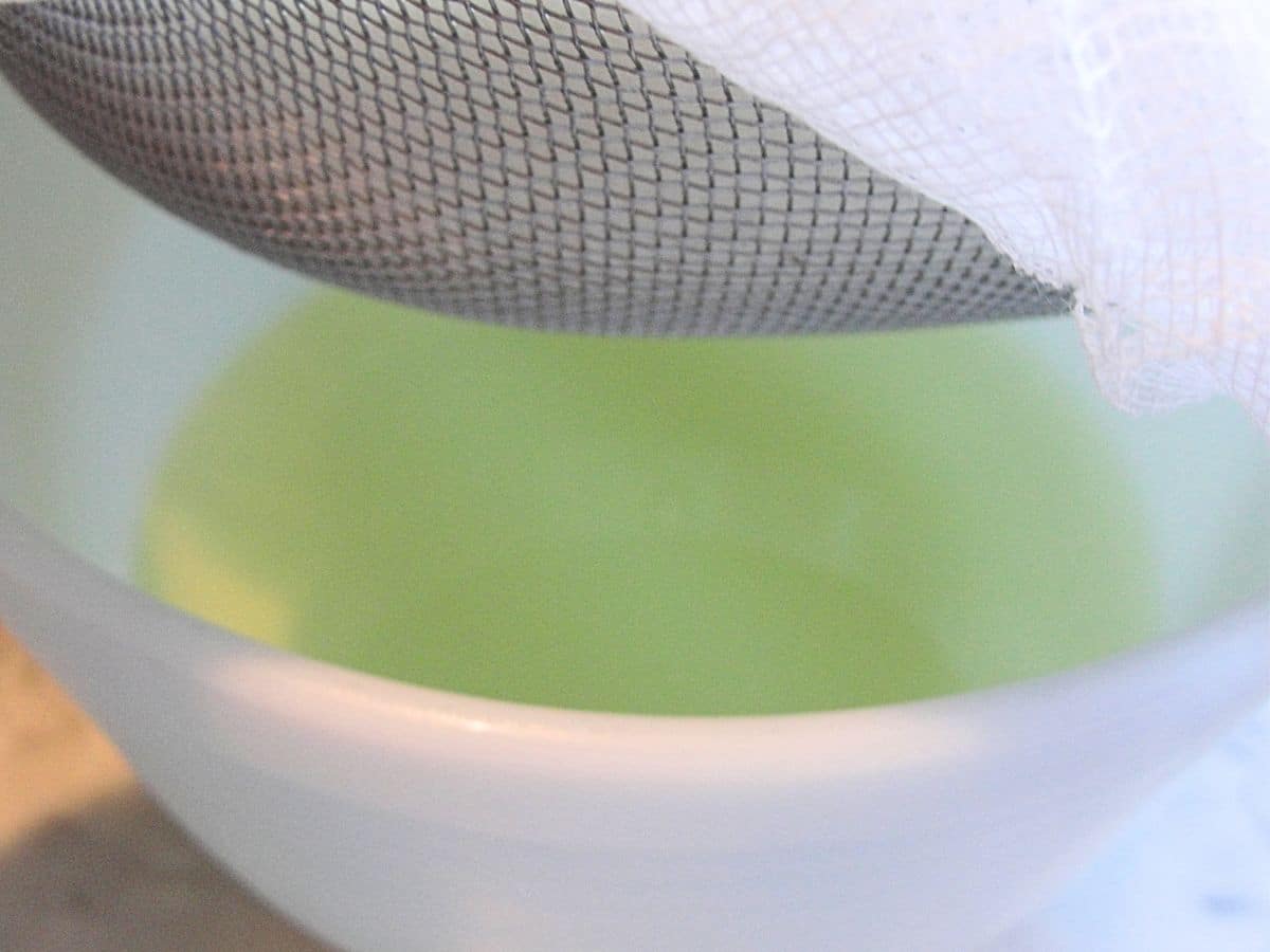 yogurt in cheesecloth lined strainer with bowl of whey underneath