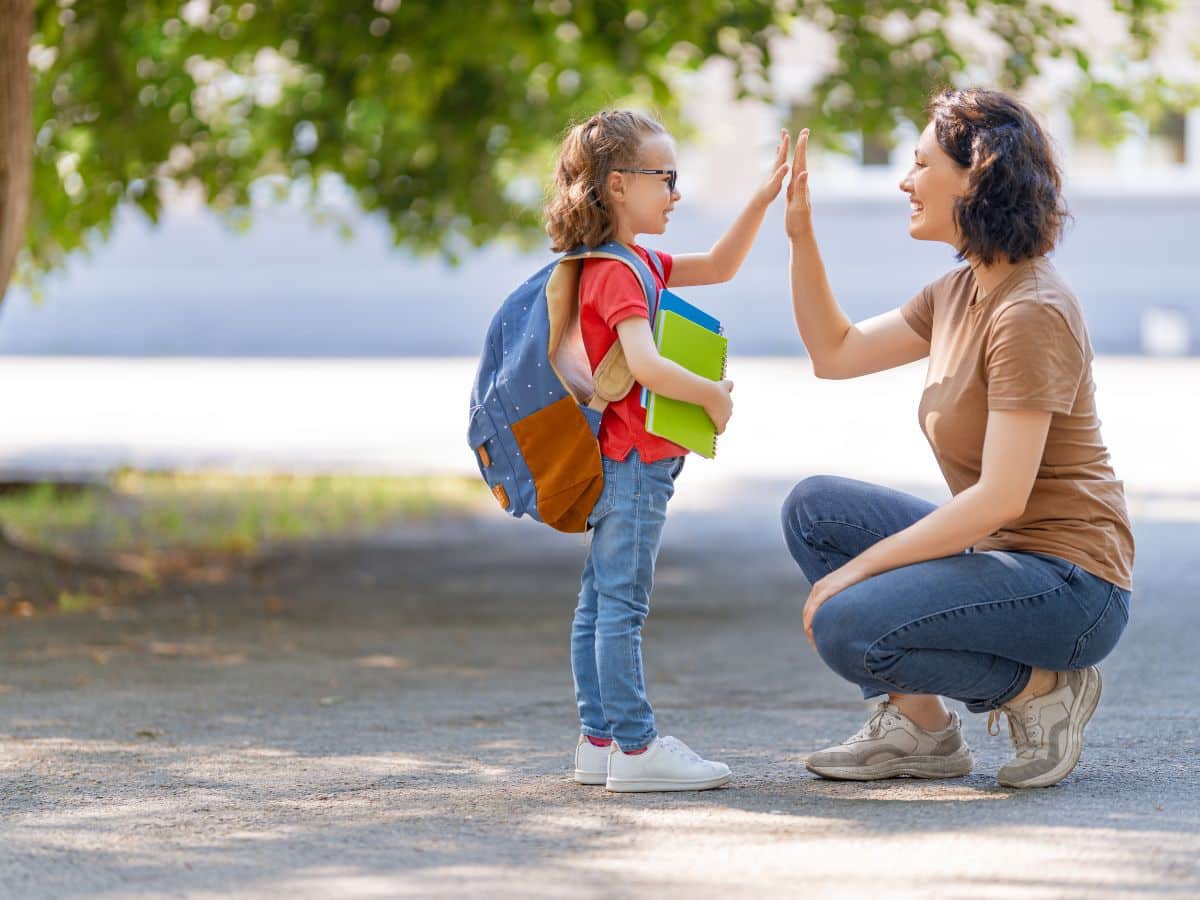 mom and child share a high five while walking to school