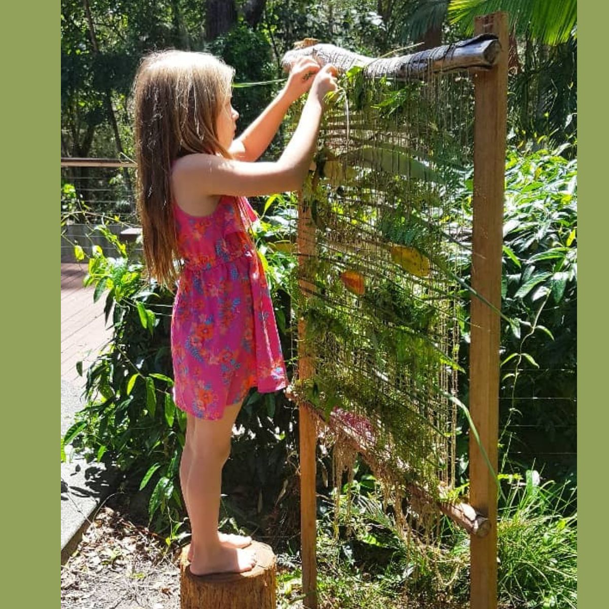 child standing at a diy backyard weaving wall
