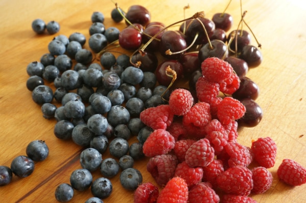 blueberries, raspberries and cherries on cutting board