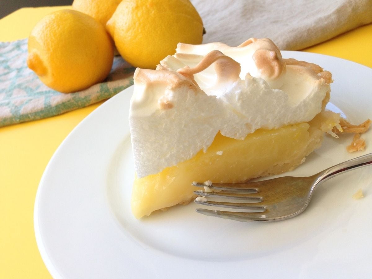 slice of lemon meringue pie on plate with fork