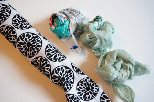 tube of fabric for draft stopper with a pile of plastic bags folded and ready to be stuffed inside