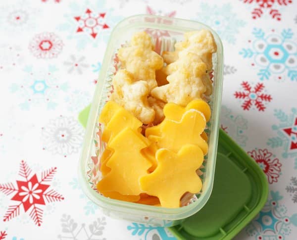 christmas crackers and cheese shaped like gingerbread people and Christmas trees in a lunch container