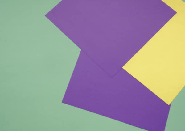 pile of purpe and yellow origami paper for folded paper snowflakes