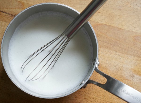 steamed milk in pot with whisk