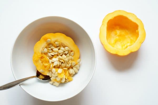 diy bird feeder pumpkin with seeds being scooped out with spoon and bowl