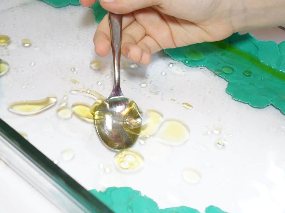 oil spill cleanup with a spoon in a child's hand