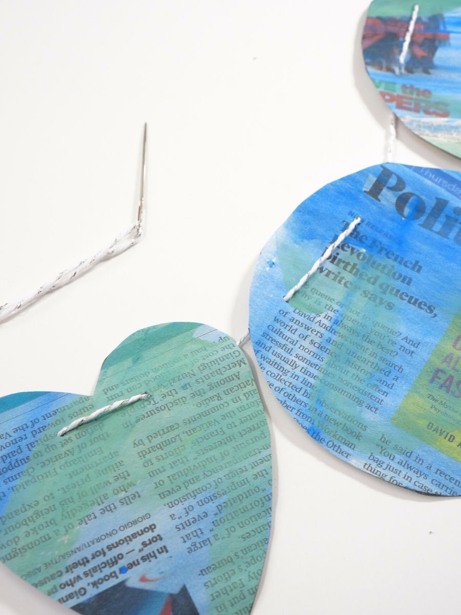 Recycled Newspaper Earth Day garland string and needle poked through newspaper earth