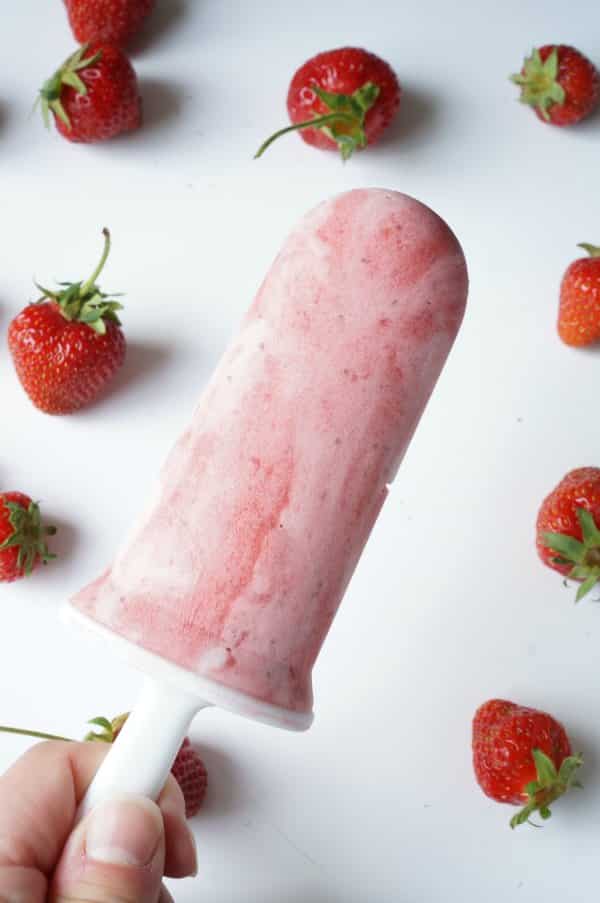 single strawberry and cream popsicle in persons hand