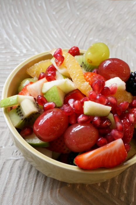 bowl of fruit salad recipe - with pomegranate, oranges, kiwi, apple and strawberries and grapes and blackberries