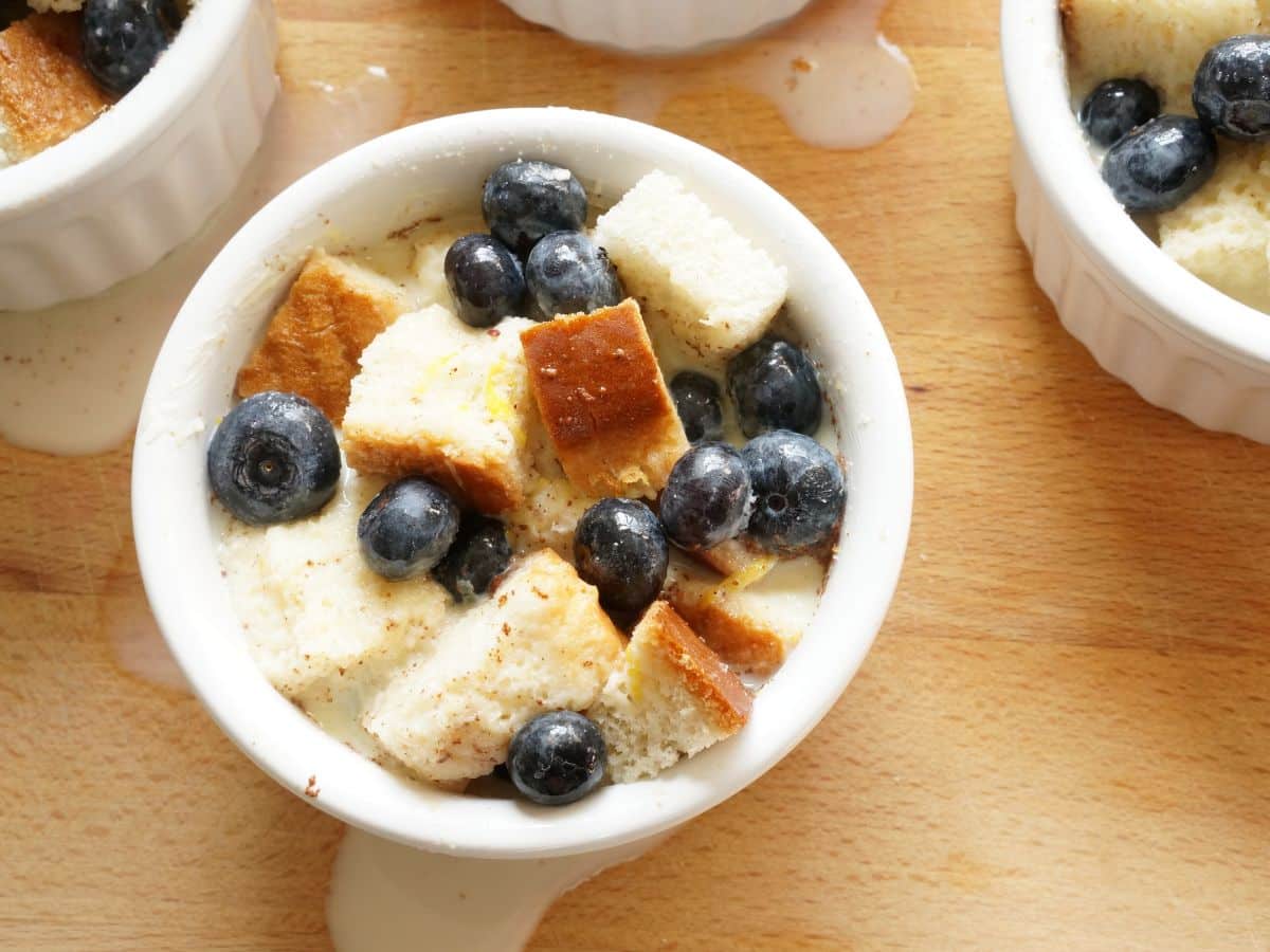 ramekins filled with cubed bread and blueberries with bread pudding batter