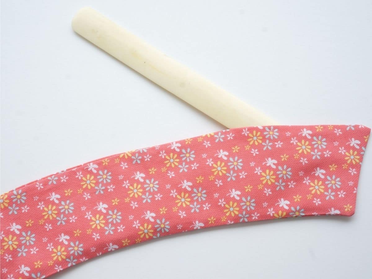bone folder poked inside cotton coffee sleeve pressing the felt and corners into place