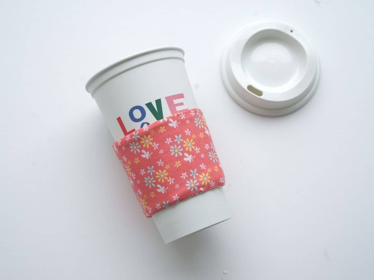 finished reusable coffee cup sleeve on a starbucks coffee cup that has the word love on it