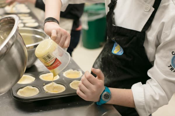 kid pouring butter tart filling