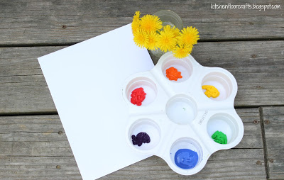 dandelion paint brushes in a jar with paints and paper