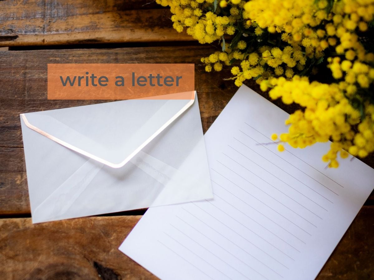 writing paper and yellow flowers with words write a letter