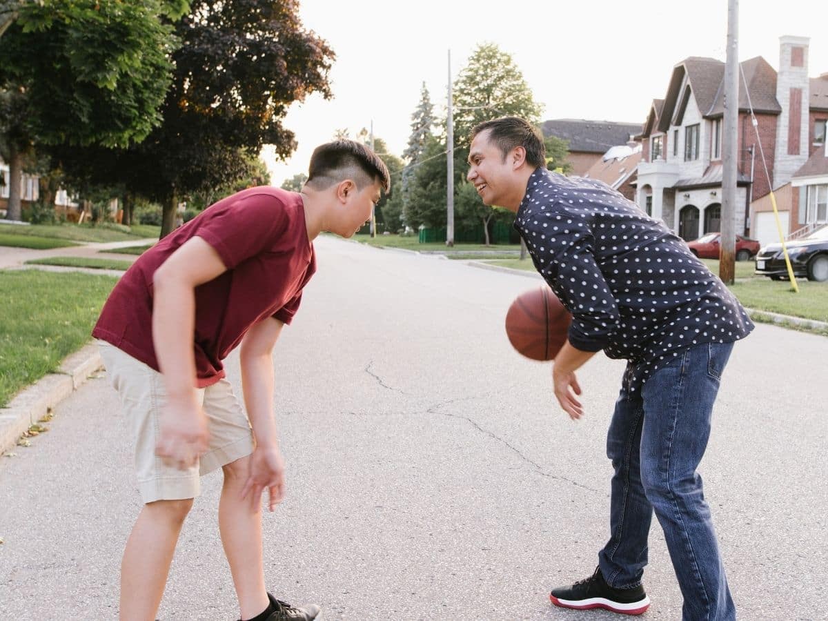 dad and son playing basketball on street