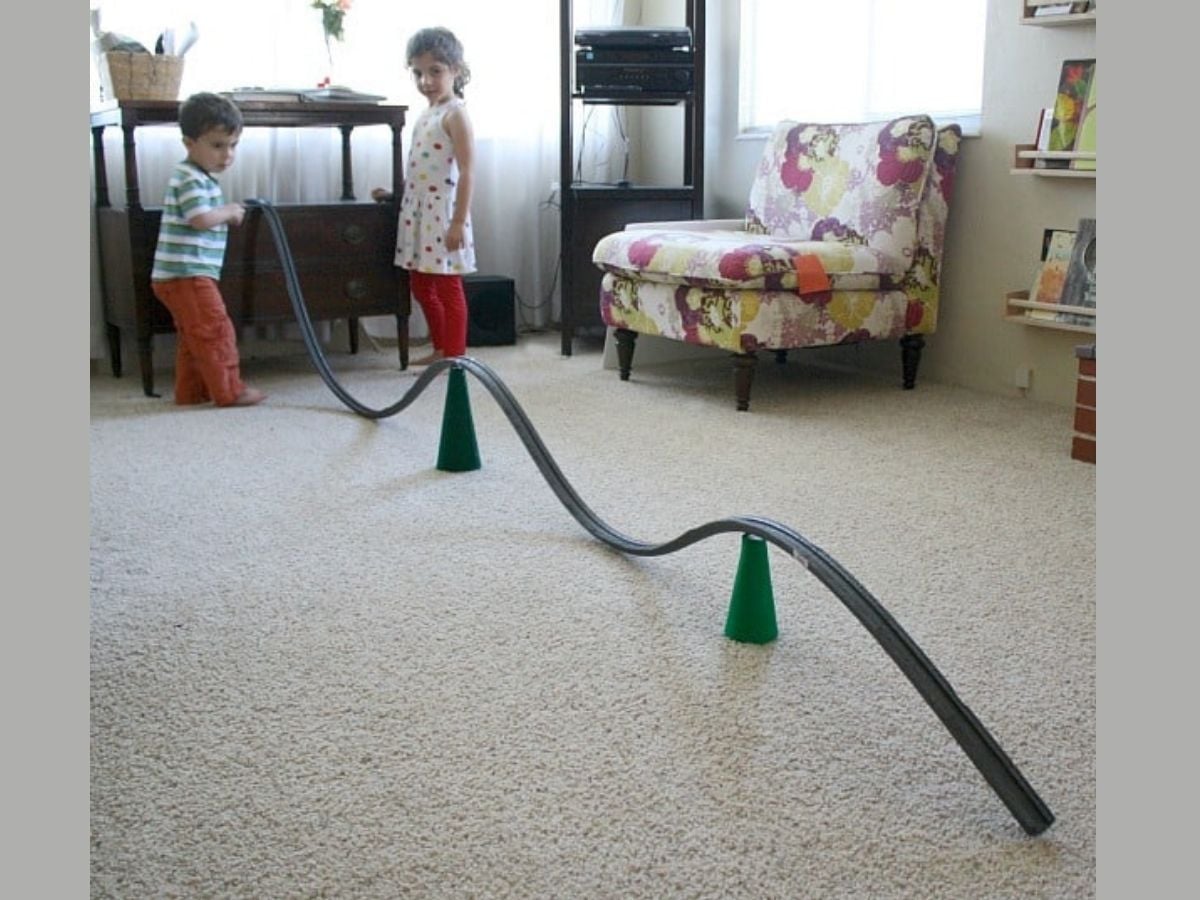 kids standing with giant marble run that runs across the livingroom