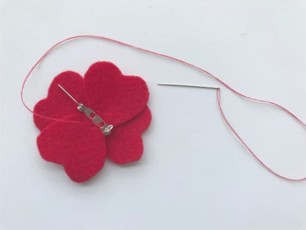 felt poppy with brooch pin being sewn on