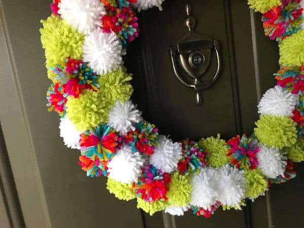 closeup of Christmas pompom wreath hanging on a front door