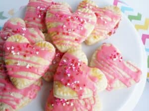 white plate with many valentine heart pop tarts with strawberry filling