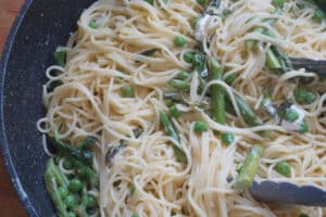 spring pasta primavera with goat cheese and tongs