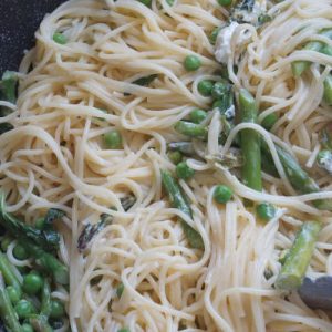 spring pasta primavera with goat cheese and tongs