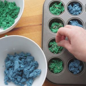 seeds being sprinkled into seed bomb muffin tin