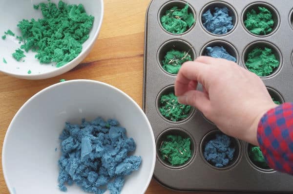 seeds being sprinkled into seed bomb muffin tin