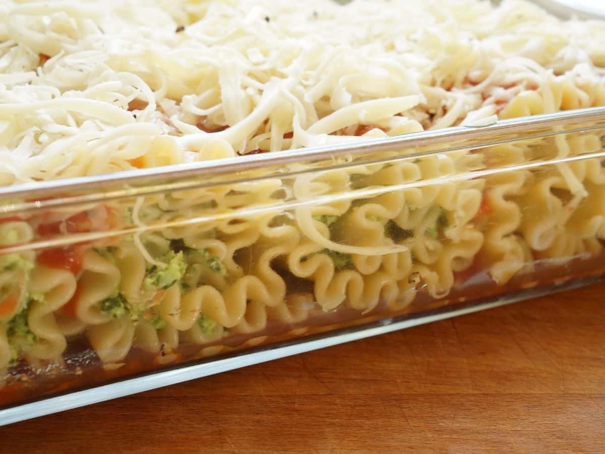 side shot of meatless lasagna rolls unbaked in pan with cheese and sauce on top