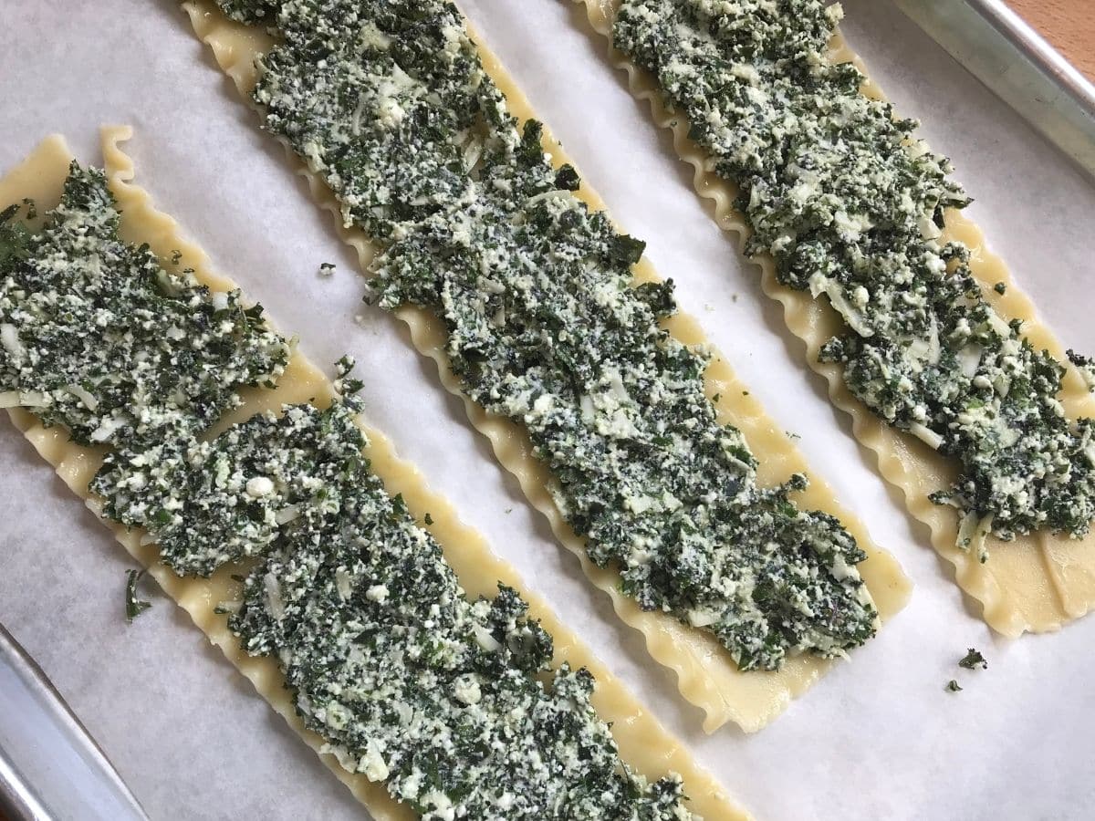 vegetarian lasagna rolls fill with kale and cheese ready to roll on parchment paper