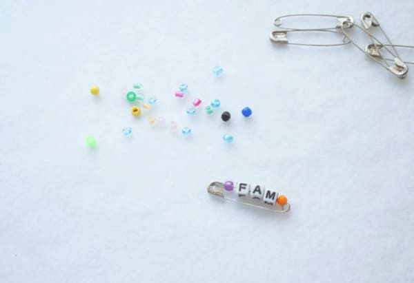 friendship pin with letter beads that say "fam"