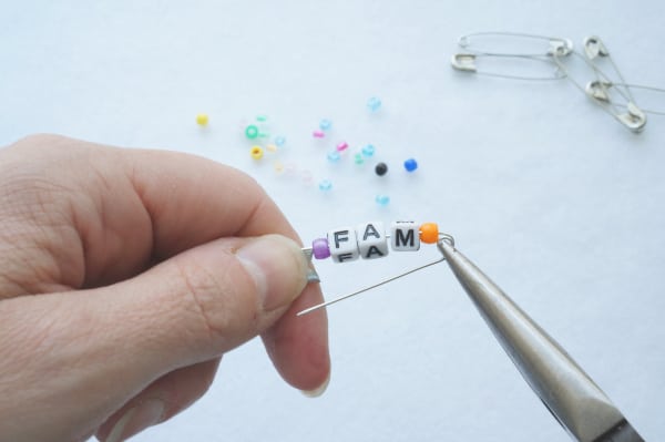 pliers closing the safety pin with the beads in place