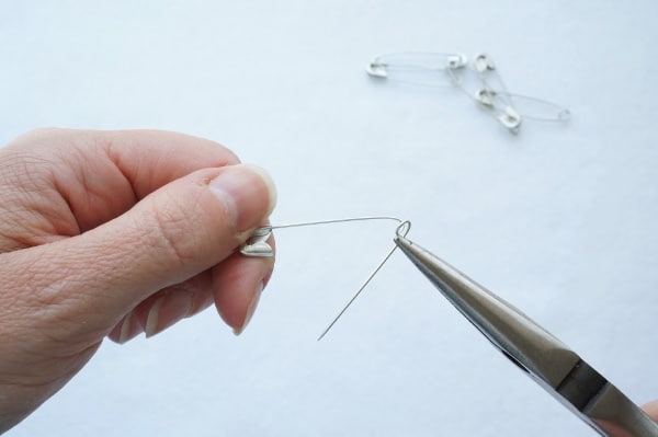 pliers with safety pin opening the end of the safety pin