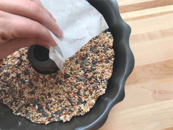birdseed wreath bird feeder dried in bundt pan - hand removing the birdseed wreath from the pan