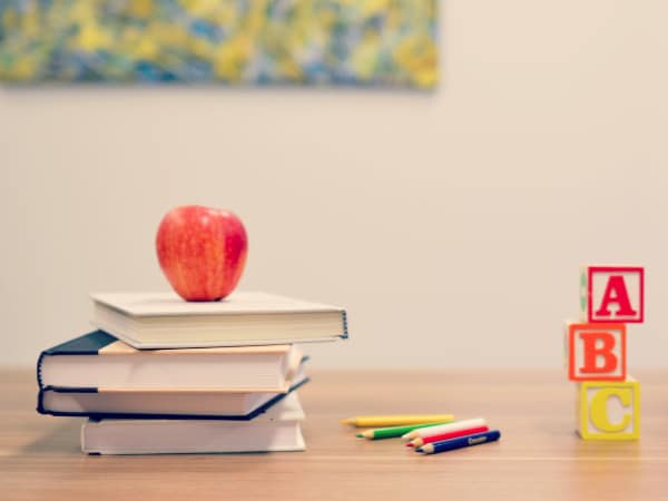 pile of books with apple and a,b,c, wooden blocks