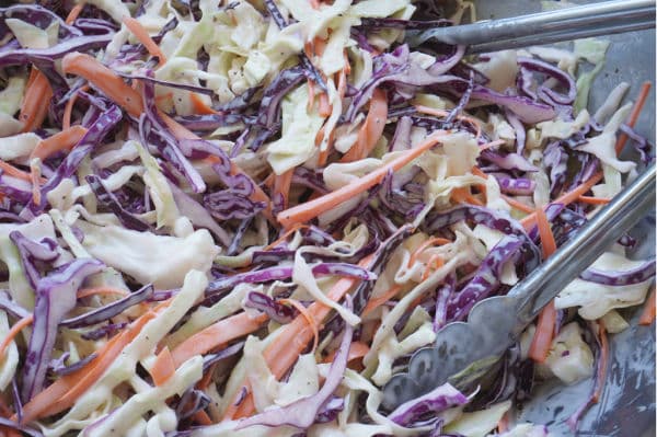 bowl of creamy coleslaw in bowl with tongs