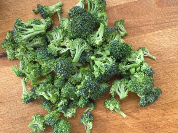 pile of broccoli florets on cutting board