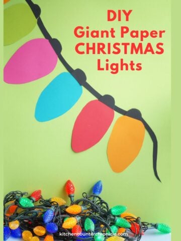 image of paper christmas lights hanging on wall with real christmas lights below them