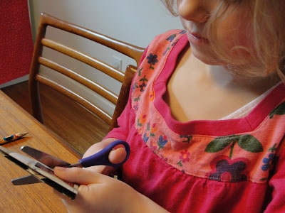 kid cutting out paper snowflake sitting at table